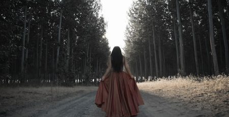 Mujer con vestido rojo en sendero del bosque. Artículo: solo yo puedo valorarme. Cely Cruz. Wola te cuenta. Somos Wola.