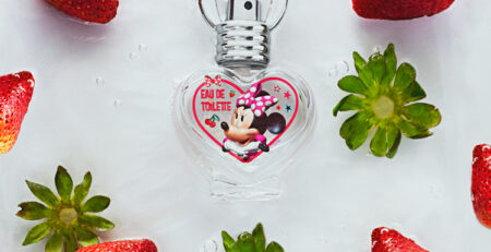 Perfume infantil de Minnie mouse sobre fondo blanco rodeado de fresas rojas todo sobre agua y burbujas. Cely Cruz, Vibra Creativa.