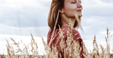 Mujer en un prado de trigo sonriendo muy feliz y tranquila. Artículo sobre Ser positivamente egoísta. Wola te cuenta. By Cely Cruz.