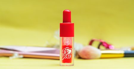 Labial tipo tinte puesto sobre fondo amarillo y cosmeticos de fondo. Foto by Cely Cruz para Vibra Creativa.