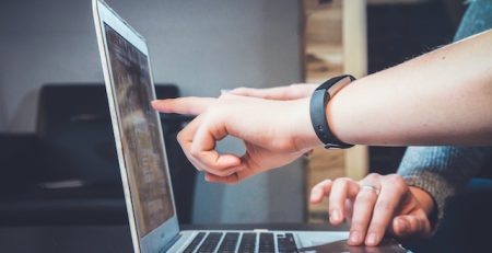 Foto de una mano señalando la pantalla de una laptop. Foto para articulo 10 problemas de la escritura en redes sociales en 2023 para Vibra Creativa.