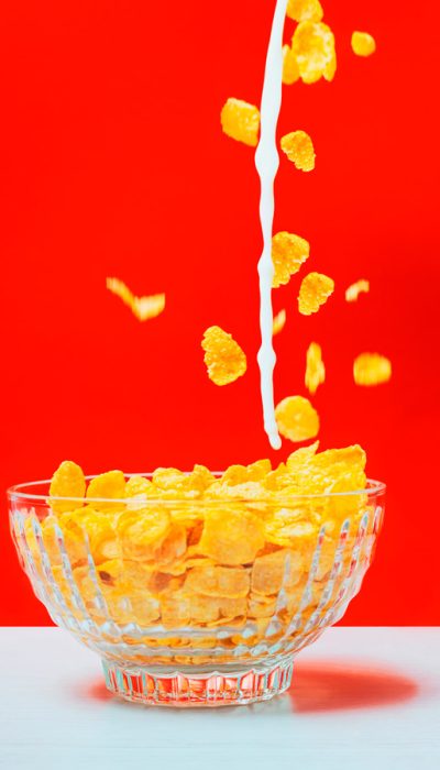 Cereal. Fotografía gastronómica. Cereal en taza transparente y lecha cayendo en movimiento.